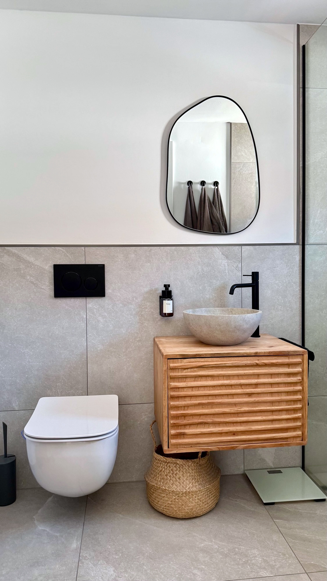 Badezimmer mit grauen großformatigen Fliesen und Waschtisch aus geriffeltem Holz