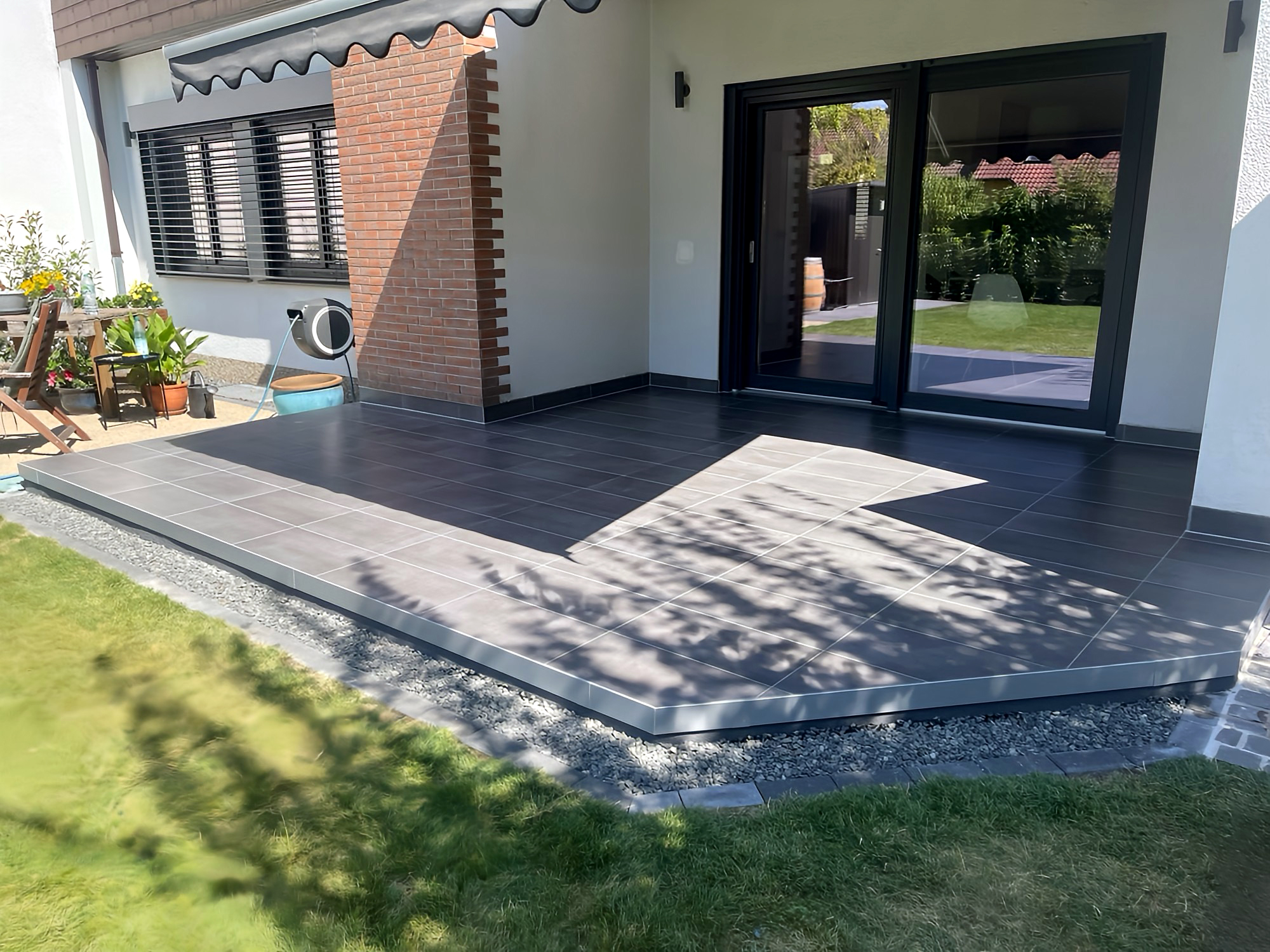 Gefliester Terrassenbereich mit großformatigen Fliesen und Gartenblick
